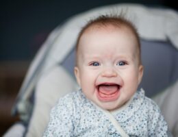 Portrait of adorable smiling baby infant showing first teeth.
