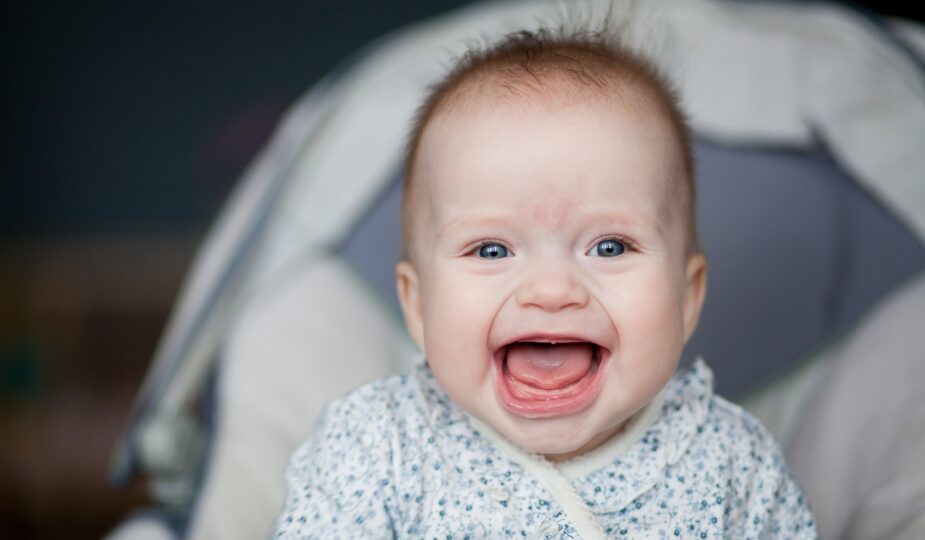 Portrait of adorable smiling baby infant showing first teeth.
