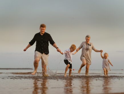 nice caucasian family having fun running in sea on sunset.Summer vacation with kids