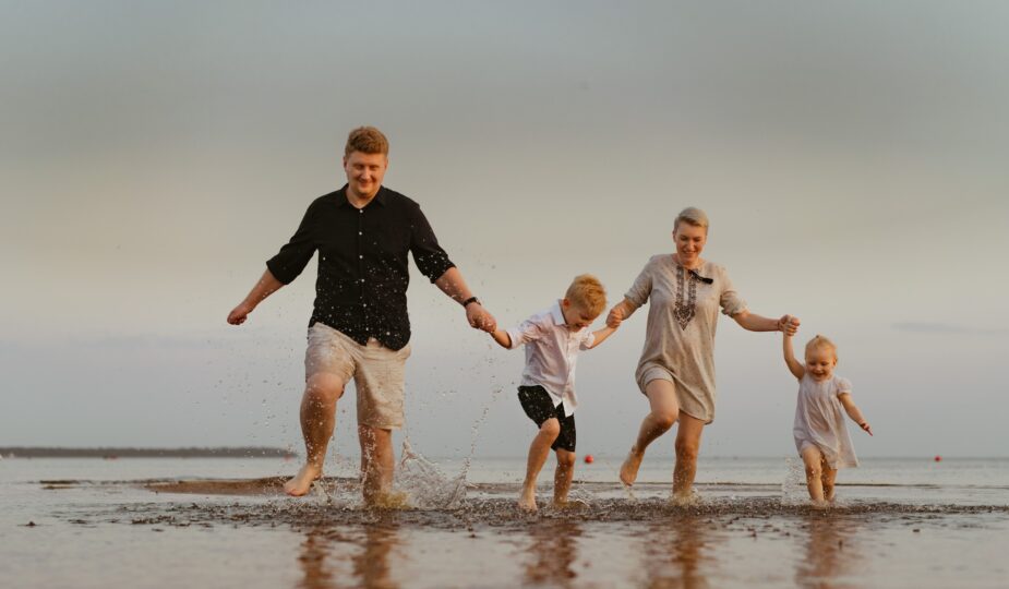 nice caucasian family having fun running in sea on sunset.Summer vacation with kids