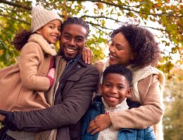 Portrait Of Smiling Family On Walk Through Countryside Against Autumn Trees