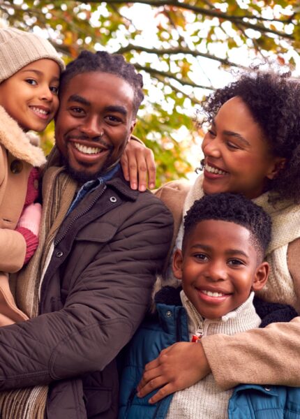 Portrait Of Smiling Family On Walk Through Countryside Against Autumn Trees