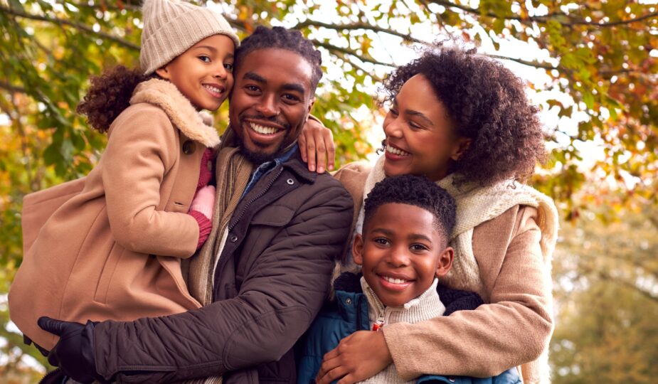 Portrait Of Smiling Family On Walk Through Countryside Against Autumn Trees